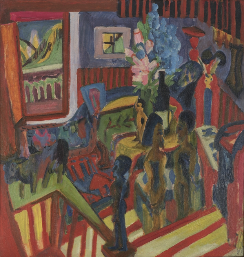 Atelierecke mit ethnografischen Objekten, Blumen, St&uuml;hlen und Tisch. Vorne ist eine Treppe. Die T&uuml;re hinten links ist ge&ouml;ffnet.