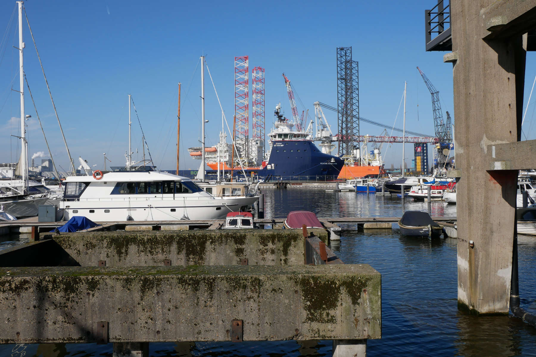 Schiffe liegen im Hafenbecken der ehemaligen NDSM-Schiffswerft vor Anker. Hinten stehen Industriekr&auml;ne.